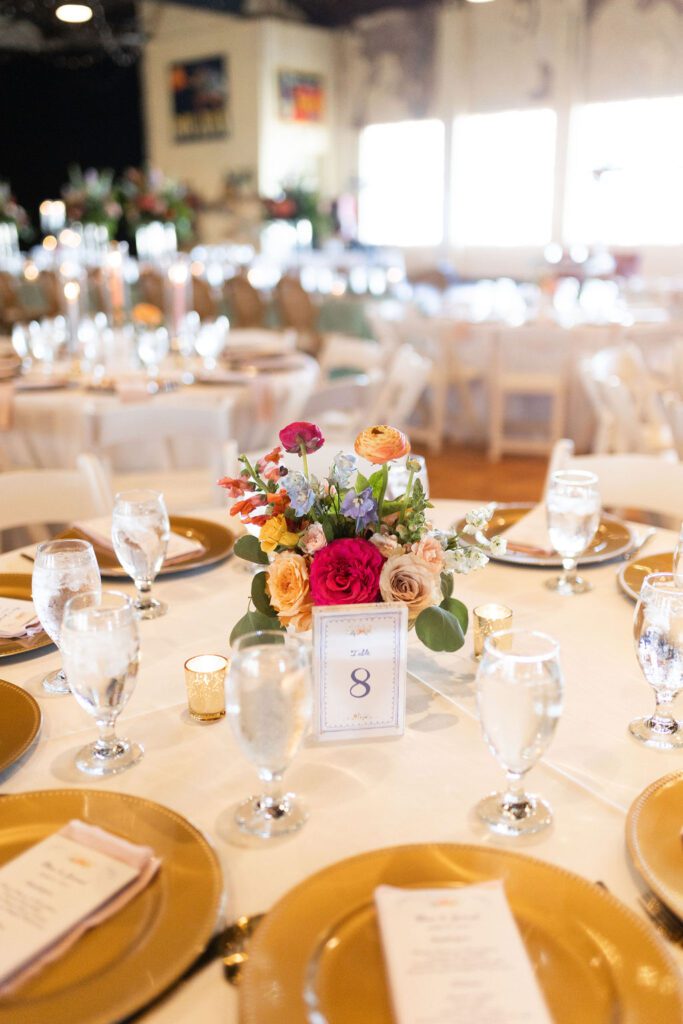 Compote floral centerpiece with gold chargers and table numbers